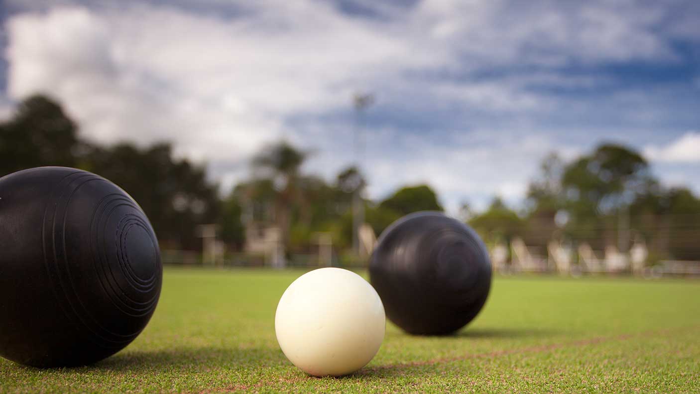 Lawn bowls with a close up photo of the bowl and jack, photographed close up low profile shot showing the green grass bowling surface in the background.