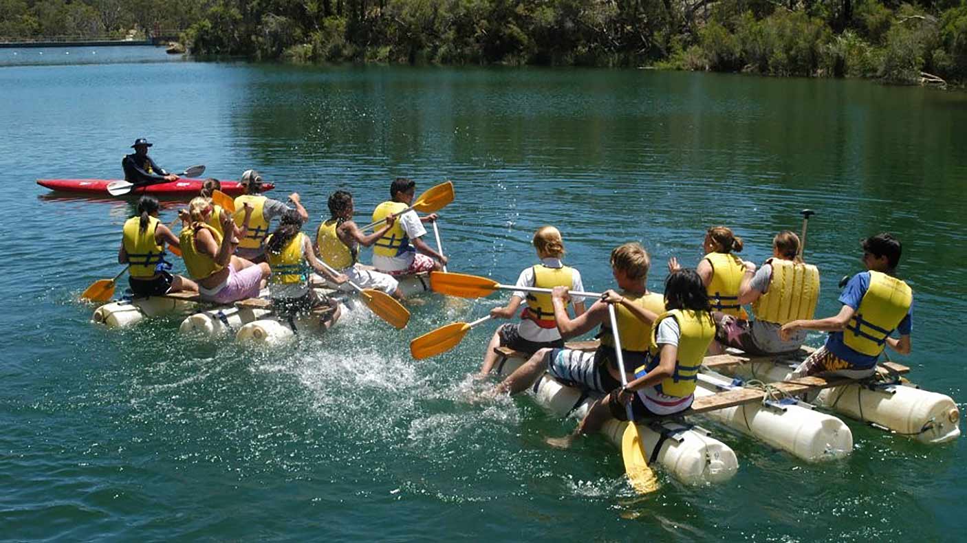 Two groups of campers paddling on rafts with an instructor