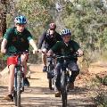 A group of three people mountain biking on a gravel trail