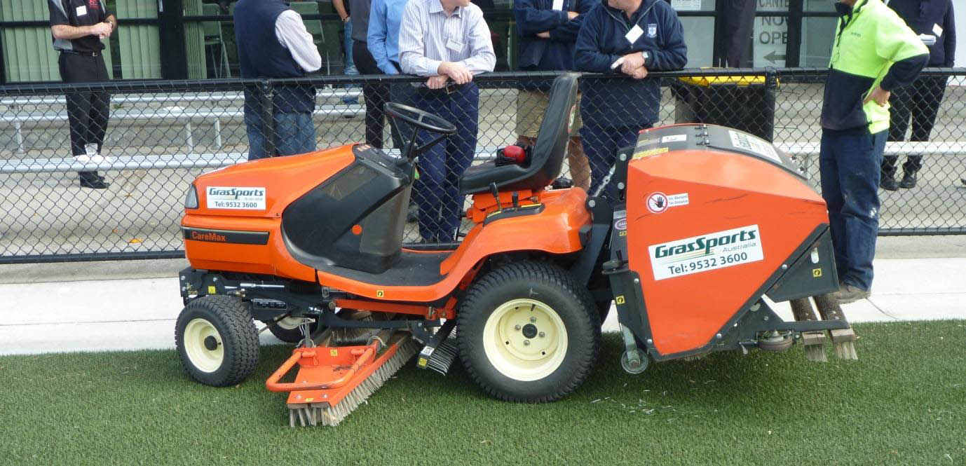 Ride on grooming and cleaning machine with petrol engine used to maintain synthetic turf.