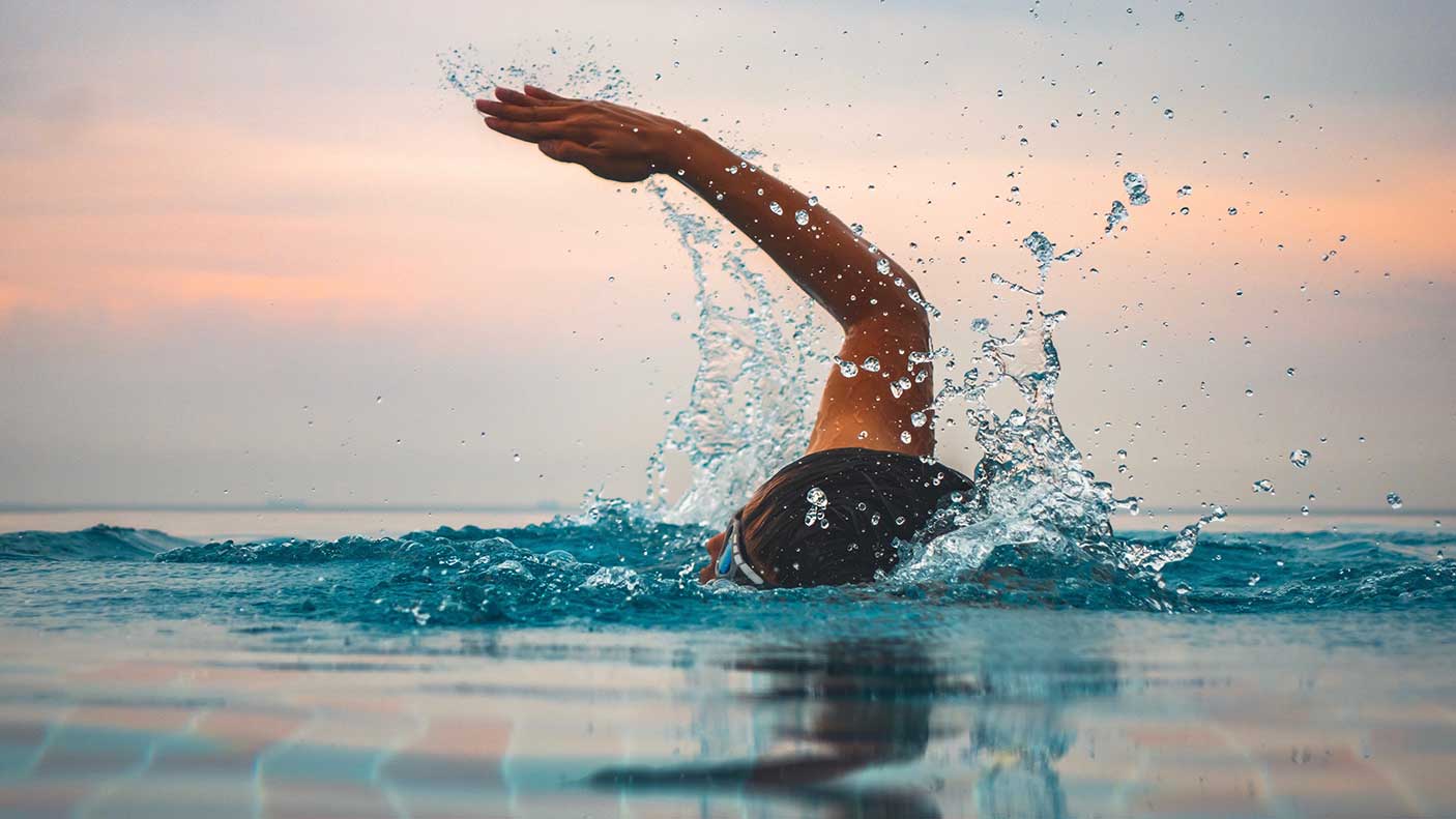 Swimmer against sky during sunset