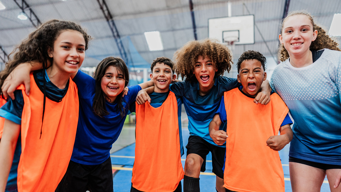 5 children huddle together on a sports court
