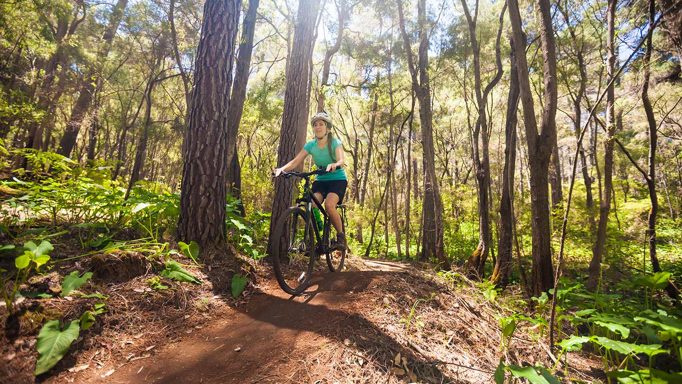 Front view of young woman mountain biking in forest