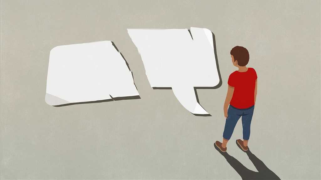 Young person looks at the ground where there is a large paper speech bubble, that has been ripped in half.